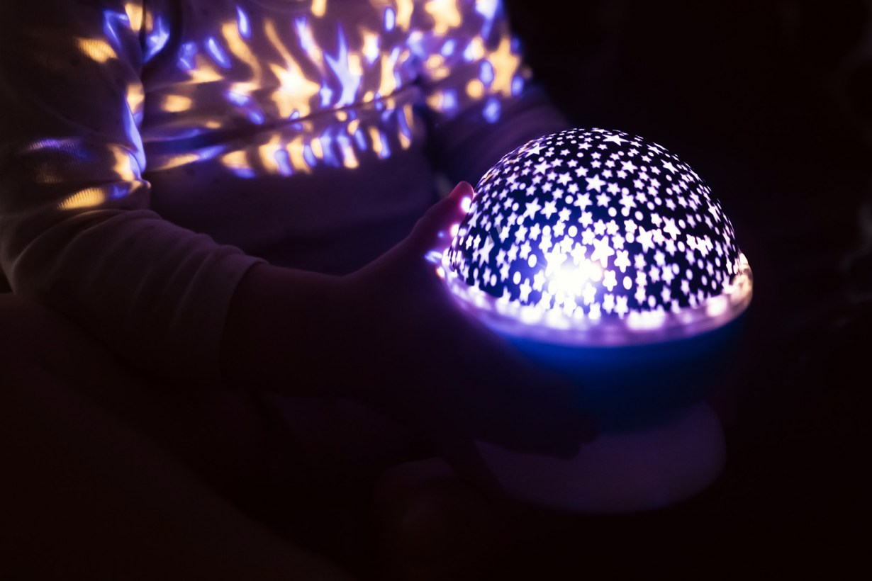 a young hand holding a galaxy projector
