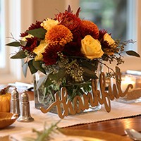 Vase full of fall flowers with :thankful&quot; sign in front