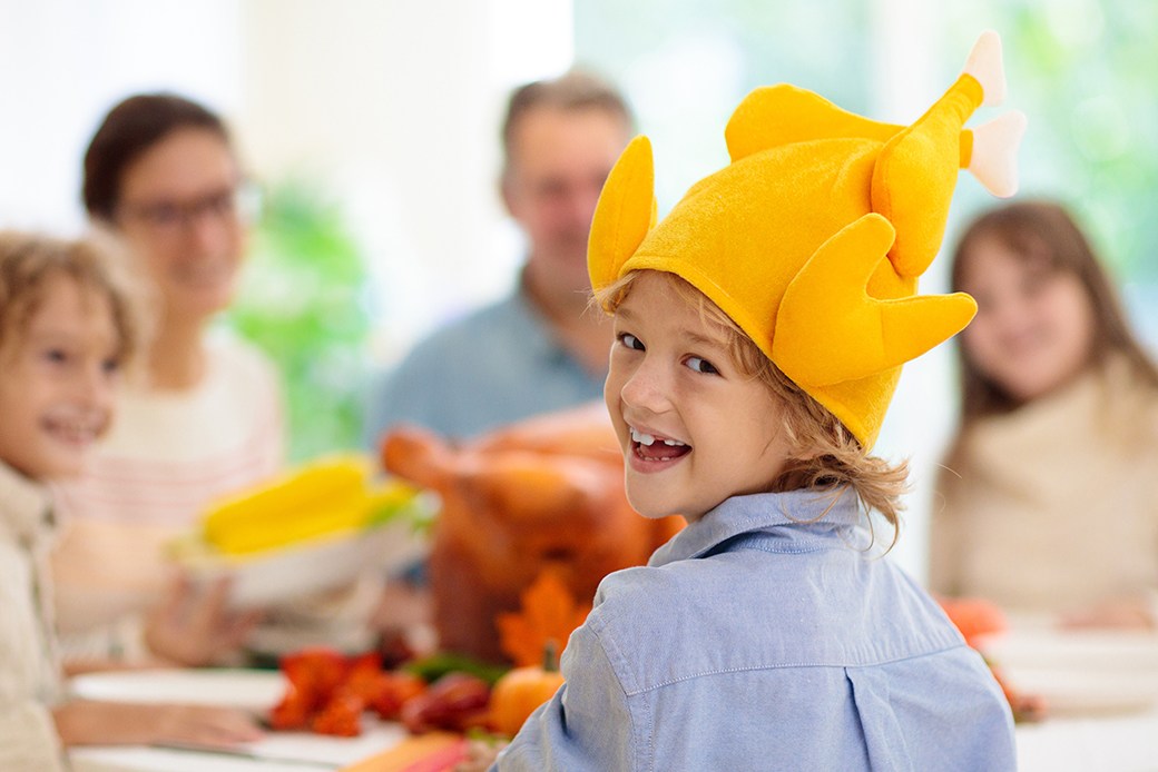 Child with turkey costume headpiece at Thanksgiving dinner table